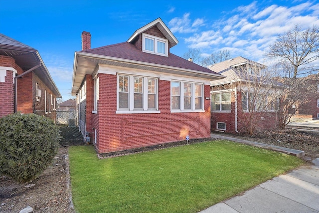 exterior space featuring brick siding, a chimney, and a front yard