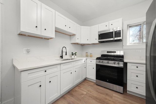 kitchen featuring a sink, white cabinets, light wood finished floors, and stainless steel appliances