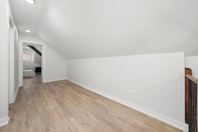 bonus room with light wood-type flooring, baseboards, and vaulted ceiling