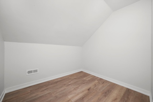 additional living space featuring lofted ceiling, wood finished floors, visible vents, and baseboards