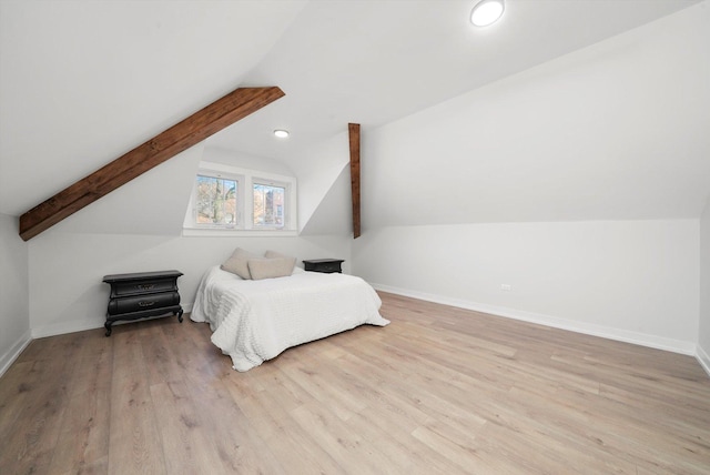 bedroom with lofted ceiling with beams, baseboards, and wood finished floors