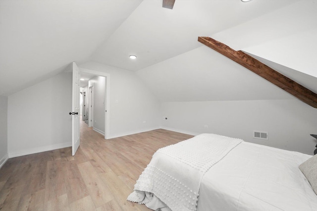 bedroom with vaulted ceiling, visible vents, baseboards, and wood finished floors