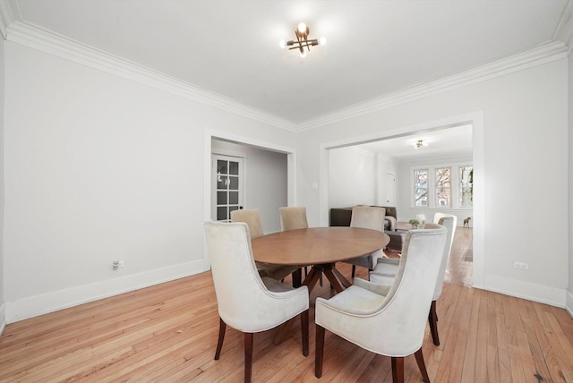 dining area with baseboards, crown molding, and light wood finished floors