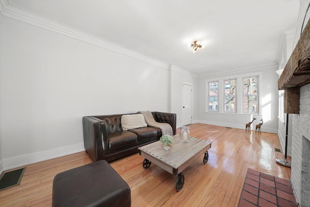 living area with visible vents, baseboards, light wood-style flooring, crown molding, and a brick fireplace