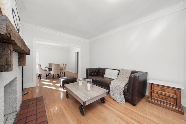 living room featuring crown molding, light wood-type flooring, baseboards, and a brick fireplace