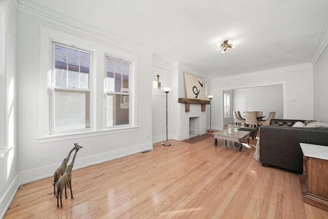 living area featuring light wood-type flooring, baseboards, ornamental molding, and a fireplace