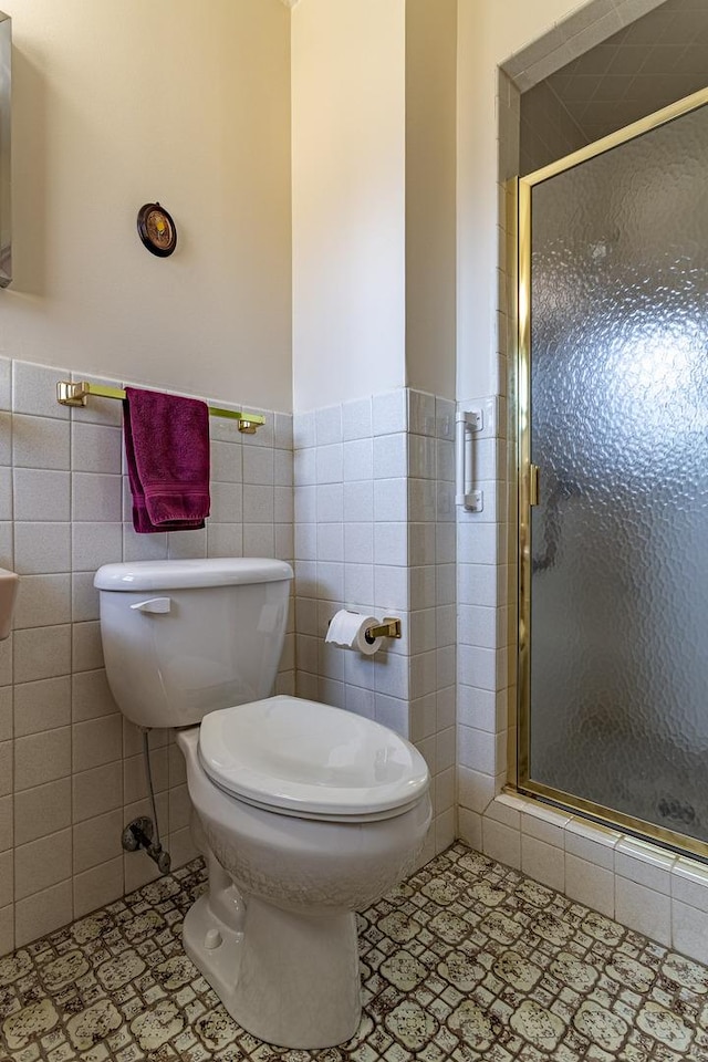 bathroom with toilet, tile patterned flooring, a shower stall, and tile walls