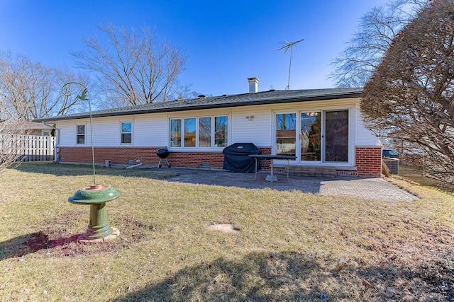 back of property with a yard, brick siding, a patio area, and fence