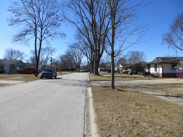 view of street featuring sidewalks, a residential view, street lights, and curbs