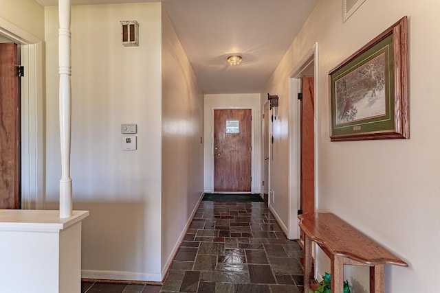 corridor featuring visible vents, stone tile flooring, and baseboards