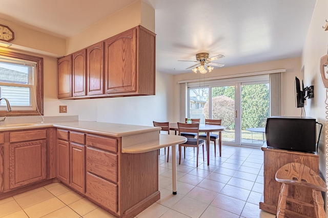 kitchen with light tile patterned floors, light countertops, a sink, and brown cabinets