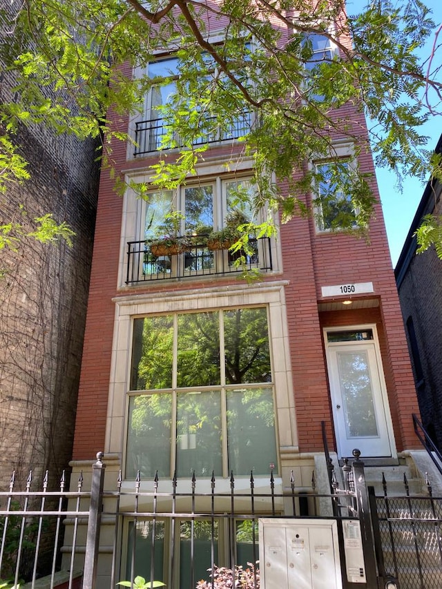 view of front of property featuring a balcony, a fenced front yard, and brick siding