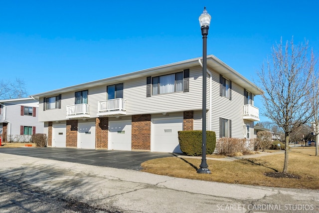 townhome / multi-family property featuring a garage, driveway, and brick siding