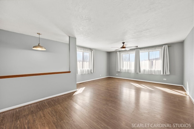 empty room with a ceiling fan, a textured ceiling, baseboards, and wood finished floors