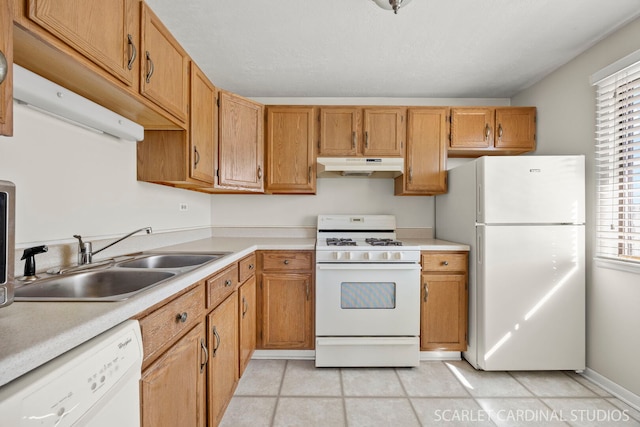 kitchen featuring light tile patterned flooring, under cabinet range hood, white appliances, a sink, and light countertops