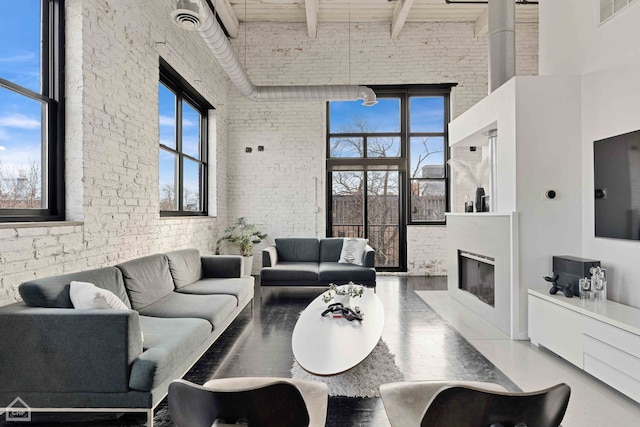 living room featuring brick wall, a high ceiling, and beamed ceiling