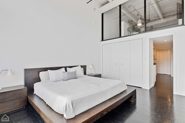 bedroom with a towering ceiling, a closet, and wood finished floors