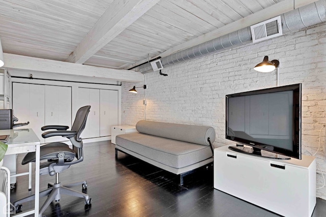 office area with brick wall, visible vents, beamed ceiling, and wood finished floors