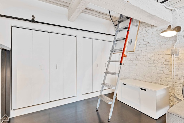 interior space with brick wall, fridge, and dark wood finished floors