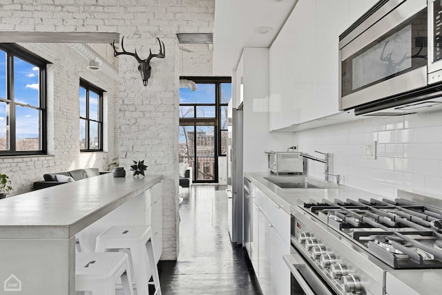 kitchen with stainless steel appliances, light countertops, a wealth of natural light, and white cabinetry