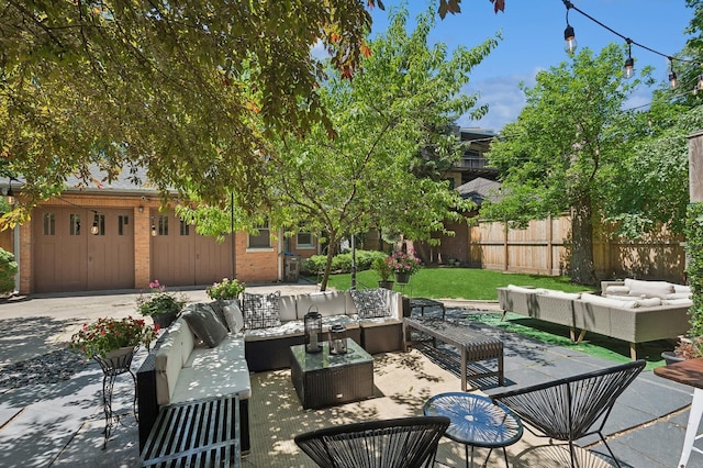 view of patio / terrace with an attached garage, fence, driveway, and an outdoor hangout area