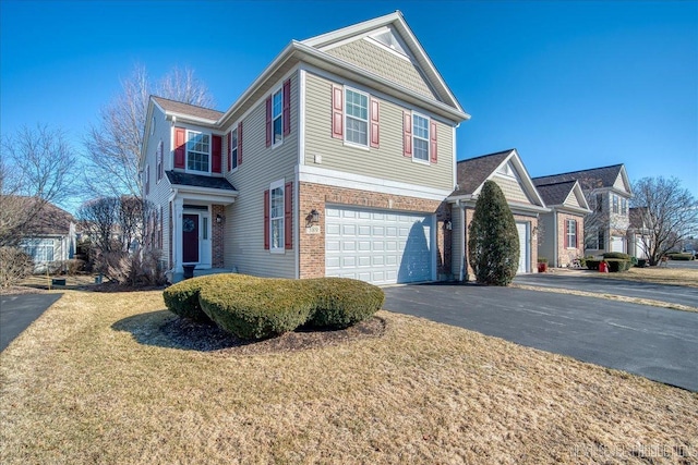 traditional-style home with a garage, driveway, brick siding, and a front yard