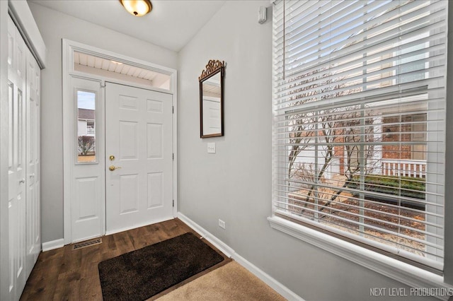 foyer entrance featuring dark wood-style flooring, visible vents, and baseboards