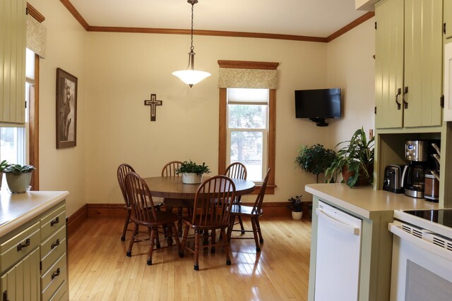 dining area featuring ornamental molding, light wood-style flooring, and baseboards