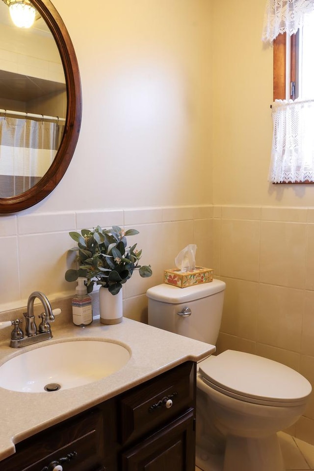 full bath featuring tile walls, a wainscoted wall, vanity, and toilet