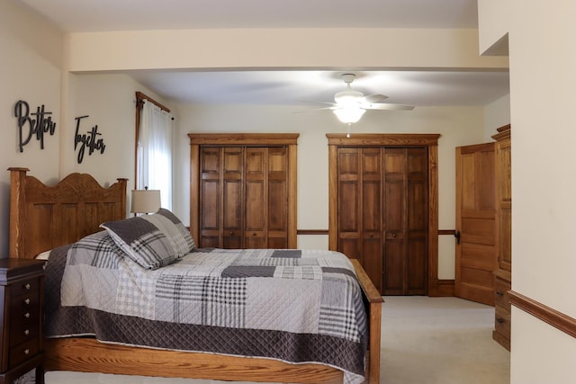 bedroom with light carpet, two closets, and a ceiling fan