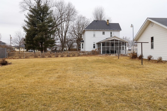 back of house with a sunroom, a chimney, fence, and a yard