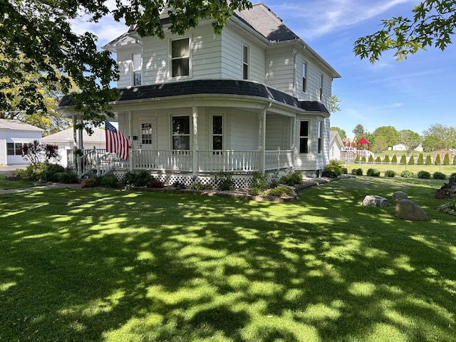 view of front of home featuring covered porch, a shingled roof, and a front yard