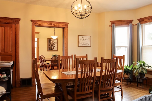 dining area featuring light wood-style floors, visible vents, and an inviting chandelier