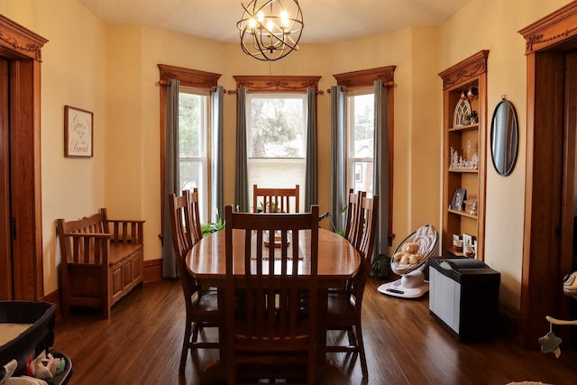 dining area featuring a notable chandelier, dark wood finished floors, and baseboards