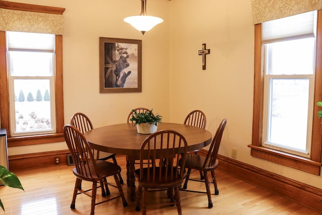 dining room with light wood-type flooring, plenty of natural light, and baseboards