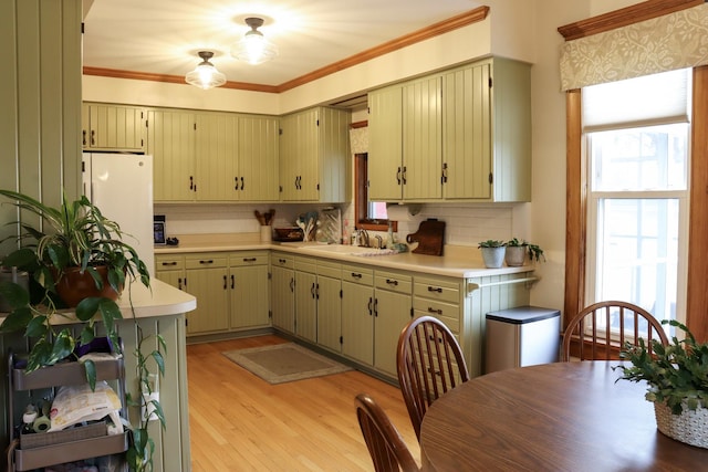 kitchen featuring tasteful backsplash, light countertops, freestanding refrigerator, a sink, and light wood-type flooring