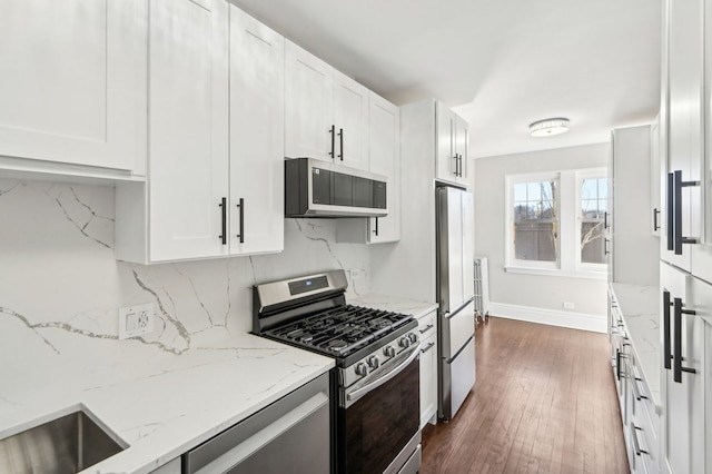 kitchen with decorative backsplash, dark wood finished floors, appliances with stainless steel finishes, light stone countertops, and white cabinetry