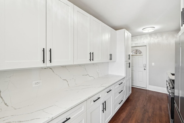 kitchen featuring stainless steel range with gas stovetop, white cabinetry, light stone counters, and dark wood-style flooring