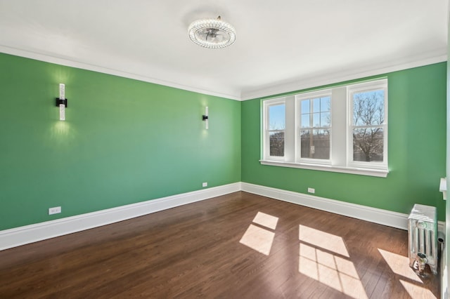 unfurnished room with radiator, crown molding, baseboards, and wood finished floors