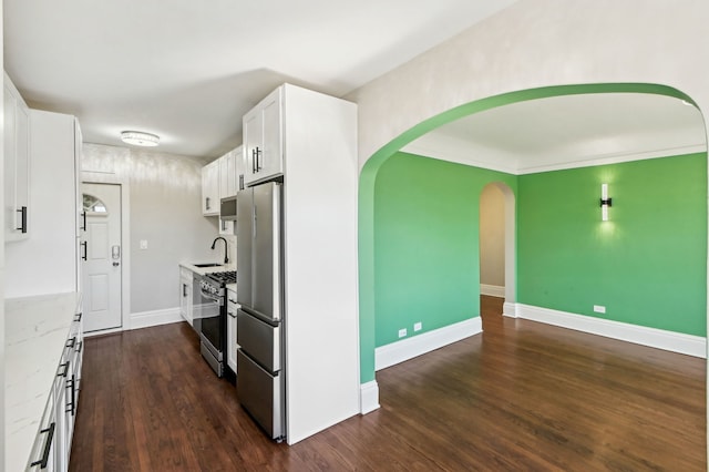 kitchen featuring appliances with stainless steel finishes, dark wood-type flooring, a sink, and white cabinets