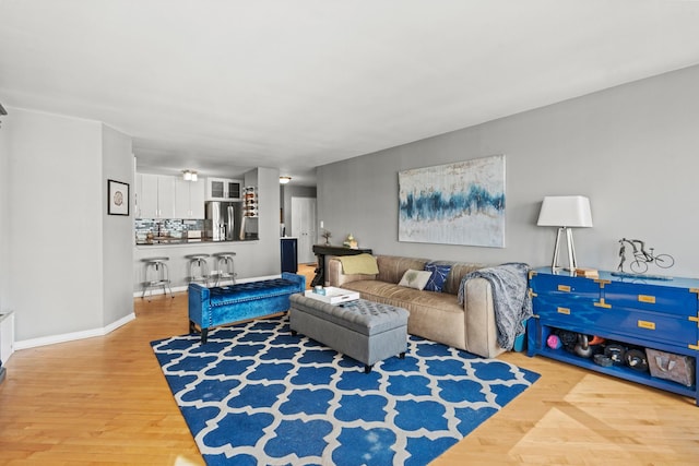 living room featuring baseboards, bar, and wood finished floors