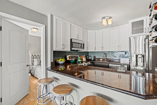 kitchen with a sink, stainless steel appliances, backsplash, and a breakfast bar area