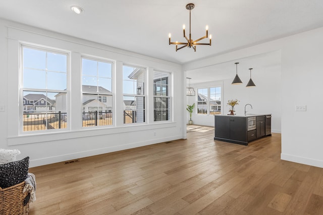 dining room with an inviting chandelier, baseboards, visible vents, and light wood finished floors