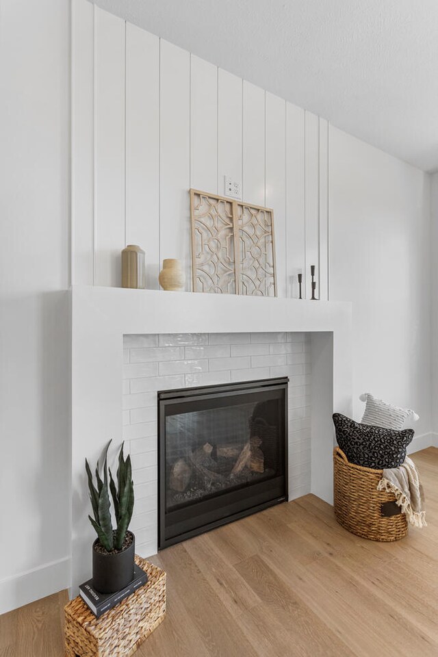 room details with baseboards, a brick fireplace, and wood finished floors