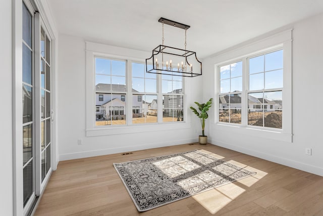 dining area featuring a notable chandelier, baseboards, and light wood-style floors