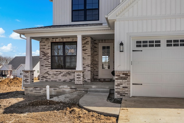 doorway to property with brick siding, a porch, a garage, and board and batten siding