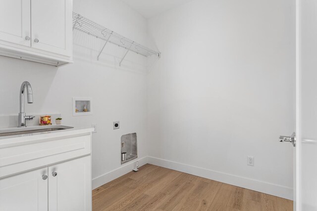 laundry room with a sink, cabinet space, light wood-style floors, hookup for an electric dryer, and hookup for a washing machine