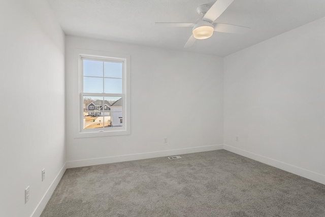 carpeted spare room featuring visible vents, baseboards, and ceiling fan