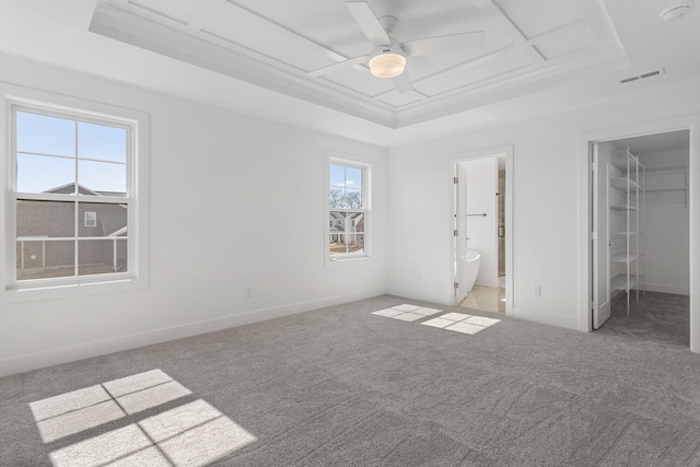 unfurnished bedroom with baseboards, visible vents, carpet floors, a tray ceiling, and a spacious closet