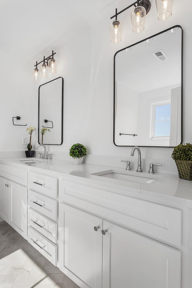 bathroom with double vanity, visible vents, and a sink